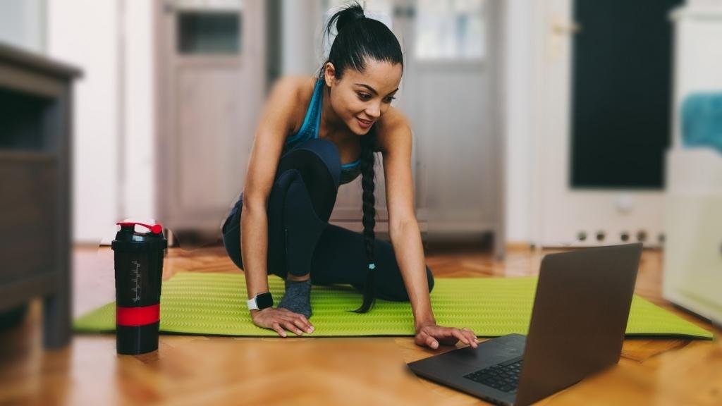 mulher pronta para fazer atividade física em casa enquanto olha o laptop